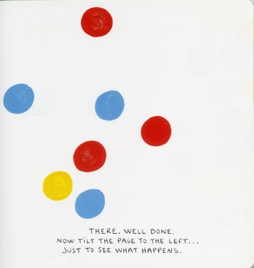 A number of dots, red, blue and yellow are strewn untidily across the page. The text says: THERE. WELL DONE. NOW TILT THE PAGE TO THE LEFT... JUST TO SEE WHAT HAPPENS.